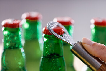 Female hand opening beer bottle using metal opener