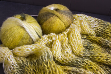 Gradient coloured yarn ball with knitted cardigan and knitting needles. Lemon coloured alpaca and...