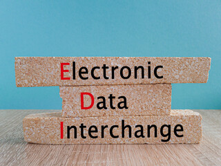 EDI electronic data interchange symbol. Concept words EDI electronic data interchange on brick blocks. Beautiful wooden table, blue background. Business and EDI electronic data interchange concept.