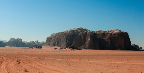 Explore the stunning rock formations and vast sandy landscapes of Wadi Rum Desert in Jordan during a clear, sunny day