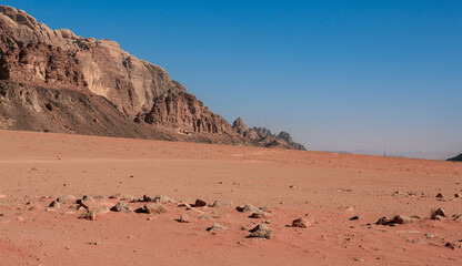 Vast sandy landscape of Wadi Rum Desert in Jordan with rocky formations under a clear blue sky