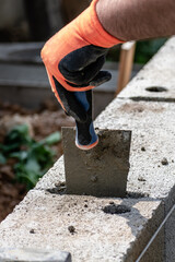 A bricklayer works on blocks to build a wall on a construction site with concrete, a trowel, a...