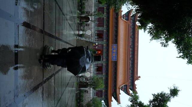 Buddhist person with umbrella at Po Lin Monastery in Lantau Island on a rainy day, Hong Kong. Vertical