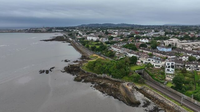 Blackrock, Dublin, Ireland, September 2024. Drone pushes south east passing Seapoint Station towards the Martello Tower following the railway line with Salthill and Monkstown in the distance.