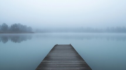 Fototapeta premium An empty dock on a calm lake, with a misty morning backdrop and subtle reflections in the water
