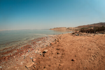 Serene landscape of the Dead Sea in Jordan showcasing the shoreline and arid terrain under a clear blue sky