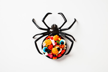 Halloween decoration spider full of candies on white background.