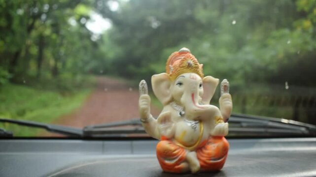 Small lord Ganesha statue of car dashboard slow-motion hd video mean while car is moving Forword on dirt road into jungle .