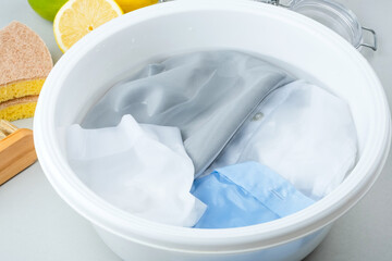 Soaking cosmetic stains on the colored fabric in a plastic basin of cold water. Natural ingredients for green cleaning alternatives. isolated. top view.