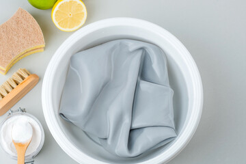 Soaking cosmetic stains on the colored fabric in a plastic basin of cold water. Natural ingredients for green cleaning alternatives. isolated. top view.