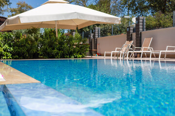 Refreshing poolside oasis with lounge chairs and an umbrella in a sunny outdoor setting