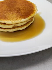 Tortitas al estilo americano con sirope de arce por encima listas para comer.
Desayuno típico americano servido en plato blanco.