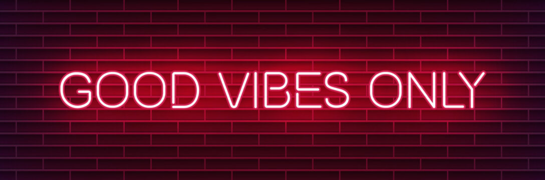 Neon sign reading "Good vibes only" on a dark brick wall