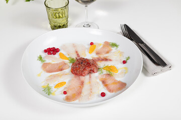 raw fish appetizer on a white plate on a restaurant table