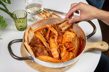 Fish broth served in a pan on a restaurant table. Fresh fish broth contains toasted bread slices. In Italy it is called Brodetto