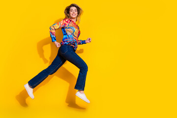 Photo portrait of active sport running woman wearing colorful pullover and jeans test her new shoes isolated on yellow color background