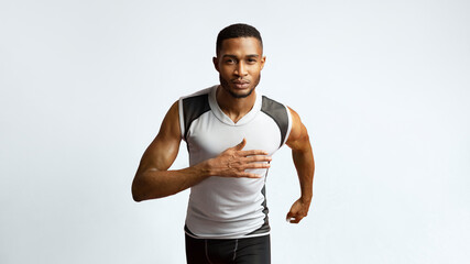 Running Competition. Confident black sportsman running, looking at camera, red background. Panorama, copyspace