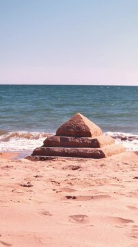 A peaceful beach scene in Islantilla, Spain featuring a handmade sand pyramid structure, surrounded by the natural beauty of the shore and ocean. Ideal for relaxation, travel, and nature content