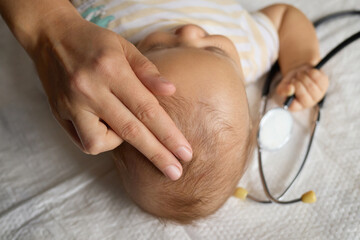 Unrecognizable pediatrician examining infant's head by gently touching the cranial bones to assess...