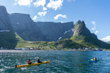 Reine, Norway - 07.07.2024: Tourists kayaking in Norwegian fishing village Reine, Lofoten Islands