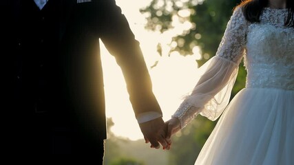 Bride and Groom Holding Hands During Golden Hour. A close-up of a bride and groom holding hands during golden hour. - Powered by Adobe