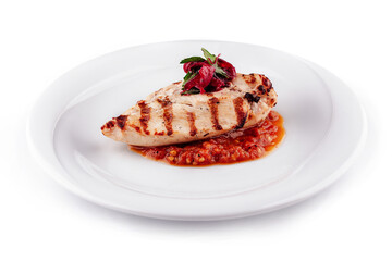 Grilled chicken breast lying on tomato sauce on white plate