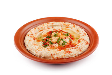 Hummus topped with chickpeas, olive oil, parsley and paprika is served on a plate