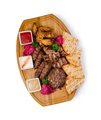 Grilled meat platter with chicken wings, sausages, burger, pita bread and sauces on wooden board
