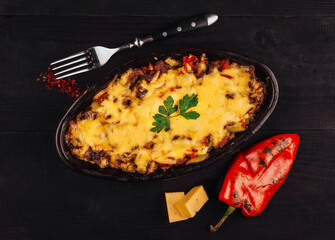 Delicious moussaka with cheese baking in a pan on a black wooden table