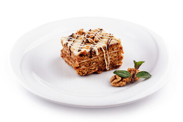 Delicious cake with walnuts and chocolate drizzle sitting on white plate