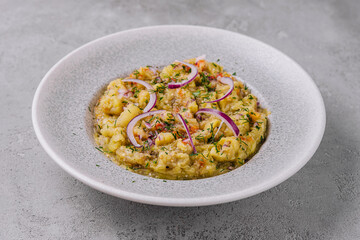 Baba ghanoush with red onions and herbs on a plate