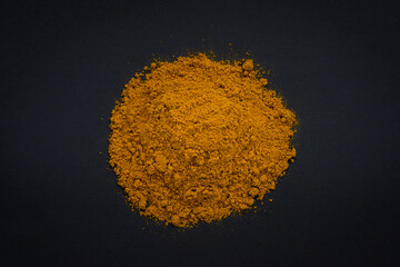Close up of curry powder in a heap on a black background
