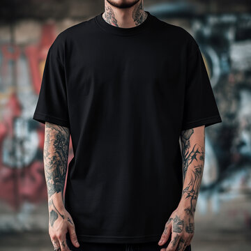 Black t-shirt mockup on a tattooed man, posed against a vibrant street backdrop featuring graffiti art, showcasing an urban vibe and casual style.