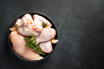 Raw Chicken with herbs and spices. Different part of chicken - fillet, wings, drumsticks on black.