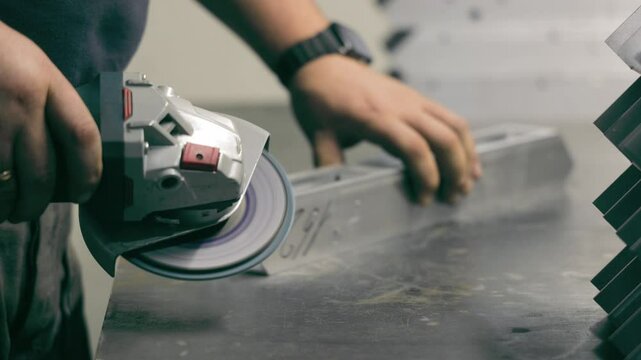 Worker grinding metal piece in a workshop. A close-up of a worker using an electric grinder on a metal piece in a workshop.