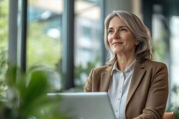 Happy mature middle aged professional business german woman bank worker or hr manager, corporate executive looking away at work working on laptop computer in office thinking of business technology fut