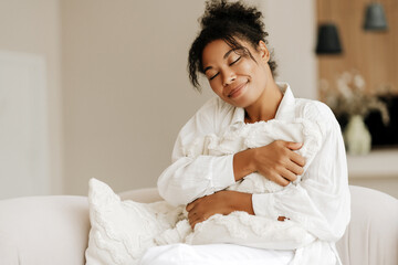 Young woman relaxing on comfortable sofa holding pillow