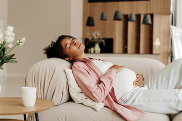 Pregnant woman relaxing on sofa taking nap at home