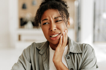 Young woman suffering from strong toothache at home