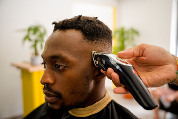 Black man getting a stylish haircut at a coast barber shop