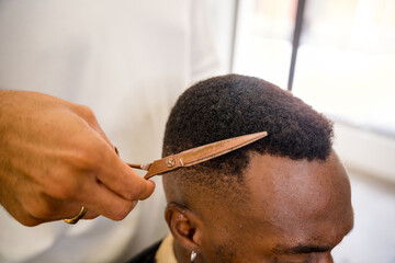 Expert barber styling hair of a black man in a shop