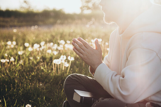 Man reading the Bible and praying in sunlight outdoors
