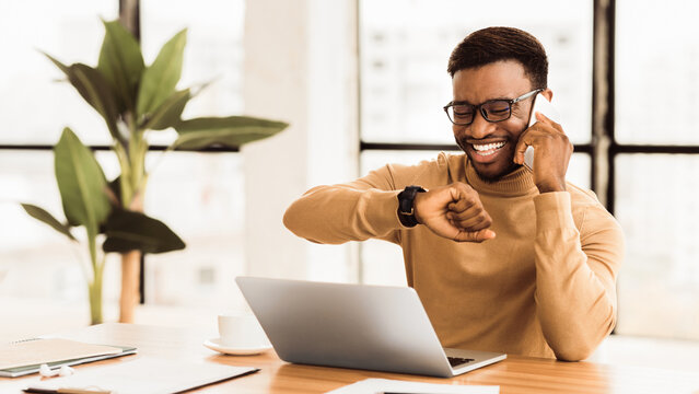 Time Is Money. African american businessman looking at wrist watch while talking on mobile phone. Panorama, copy space