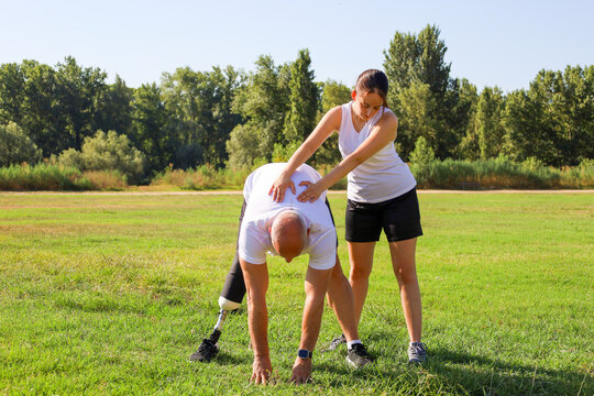 Man with a prosthetic leg exercising outdoors with his daughter