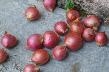 Group of fresh red shallots scattered on a rustic, rough surface