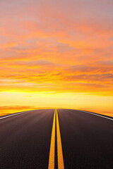Naklejka premium A scenic view of a long road stretching towards a vibrant sunset, symbolizing journeys and new beginnings.