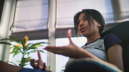 Close up of African American teenage girl sitting and talking with psychologist. Teen patient...