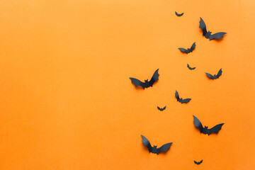 Closeup black paper bats on orange wall,copy space, decor for holiday. Interior decoration concept for happy halloween, day of the dead celebration. Top view,flat lay. Holiday postcard.