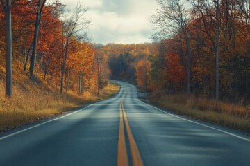 Obraz premium a scenic drive through a winding road lined with trees in full autumn color