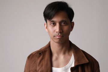 Close-up portrait of thoughtful asian man posing over white background. Vertical.